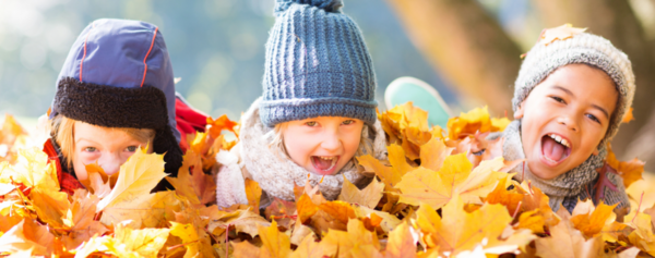 drei Kinder liegen im Herbstlaub
