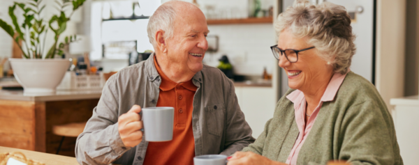 Ein älterer Mann trinkt Kaffee mit einer Dame vom Besuchsdienst