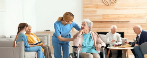 jüngere Frau unterhält sich mit älteren Dame im Rollstuhl