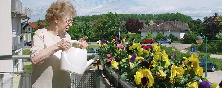 Ältere Frau gießt Blumen