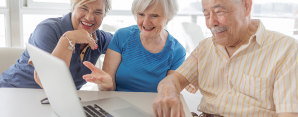 Zwei Damen und ein Herr schauen in einen Laptop