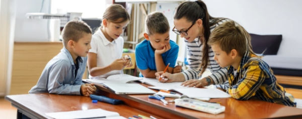 Vier Kinder und eine Lehrerin bei der Gruppenarbeit