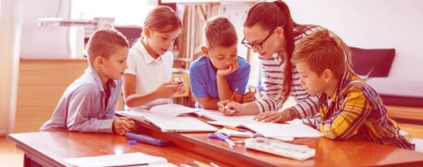 Vier Kinder und eine Lehrerin bei der Gruppenarbeit