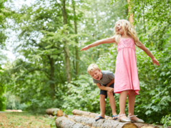 Kinder balancieren auf liegendem Baumstamm
