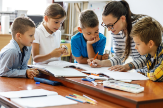 Vier Jugendliche in Gruppenarbeit mit einer erwachsenen Frau
