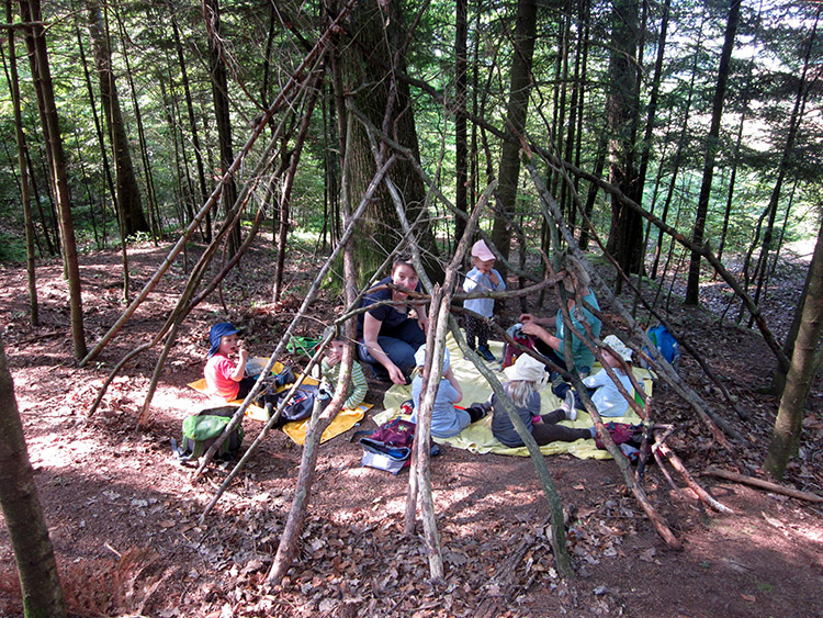 Waldkinder unter einem Zelt aus Stöcken